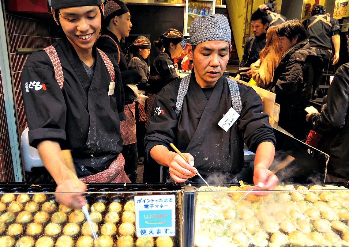 Preparing takoyaki in Osaka. You Have To Eat These Dishes in Osaka, by Boutique Japan.