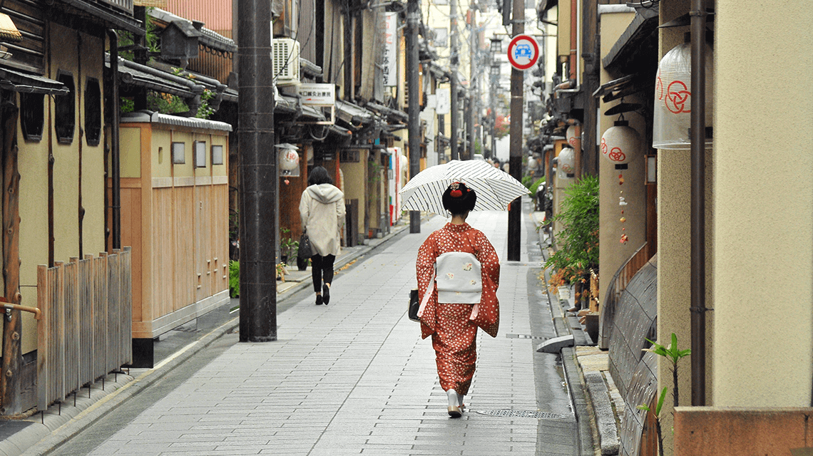 Japanese woman wearing a kimono walks down a street in Kyoto, Japan Japanese woman wearing a kimono walks down a street in Kyoto, Japan