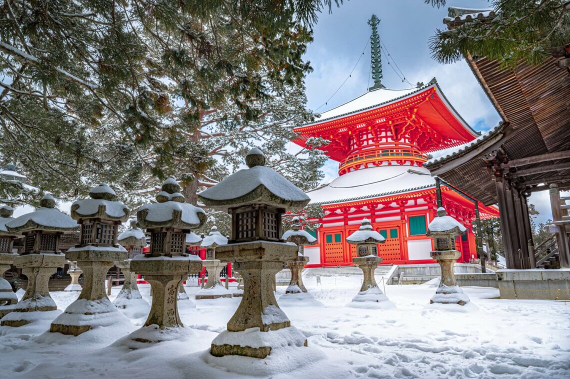 Red and white temple surrounded by trees covered with snow